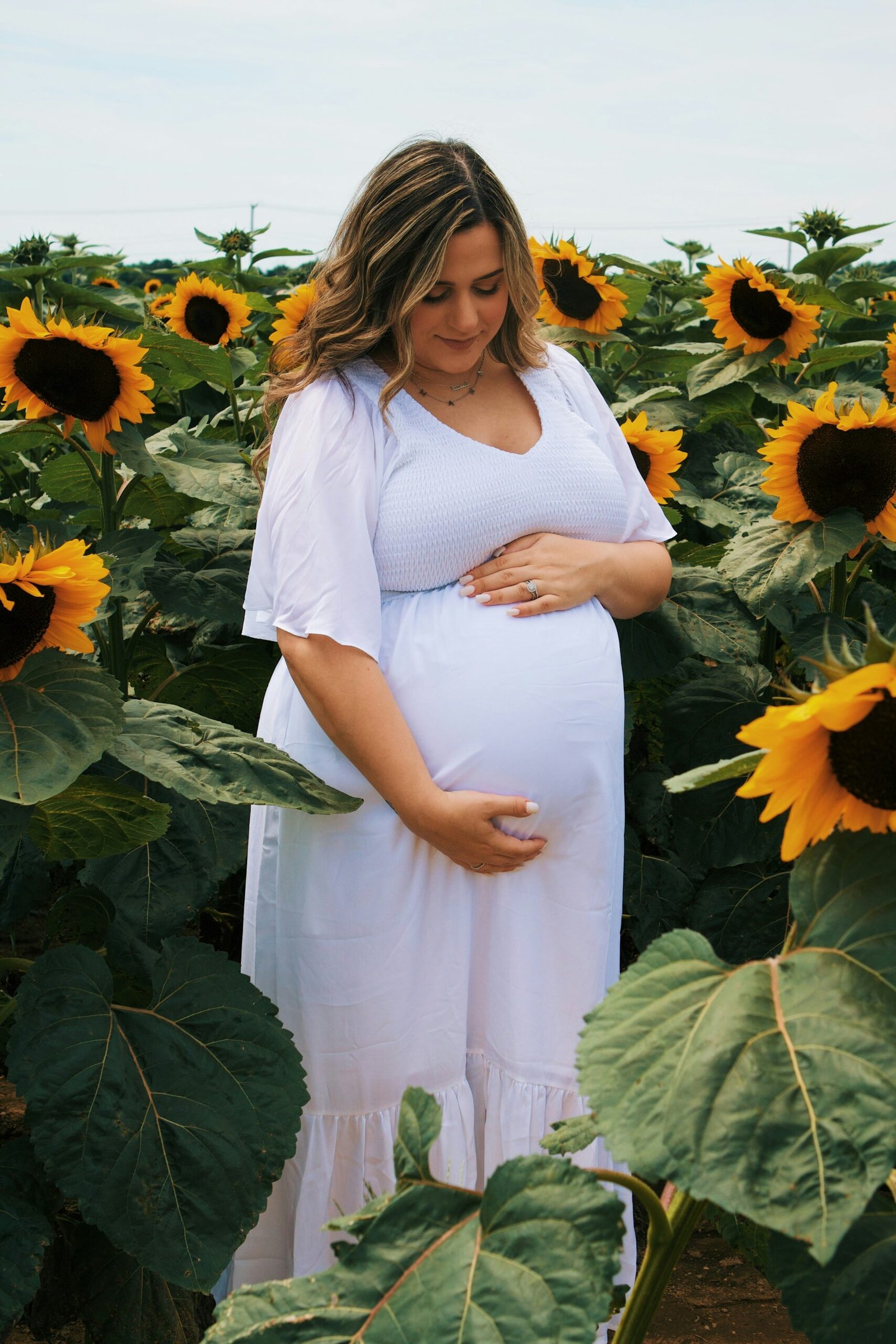 a pregnant woman standing in a field of sunflowers